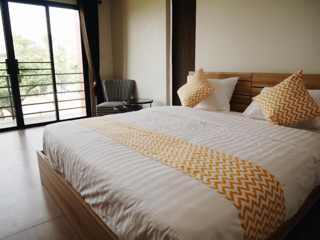 a bedroom with a large bed with yellow and white sheets at บ้านเพลิน in Nakhon Sawan