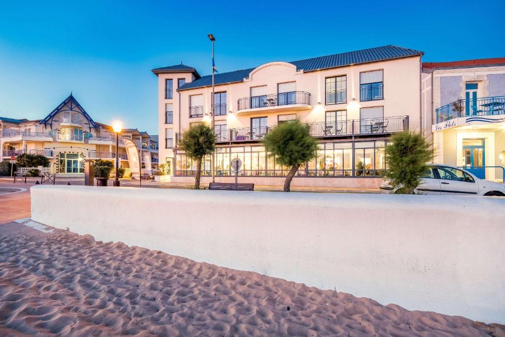 un coche blanco estacionado frente a un edificio en Les Flots - Hôtel et Restaurant face à l'océan - Châtelaillon-Plage en Châtelaillon-Plage