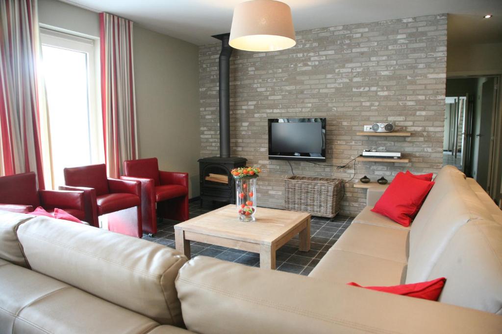 a living room with a couch and red chairs at Bloesemhof in Alveringem