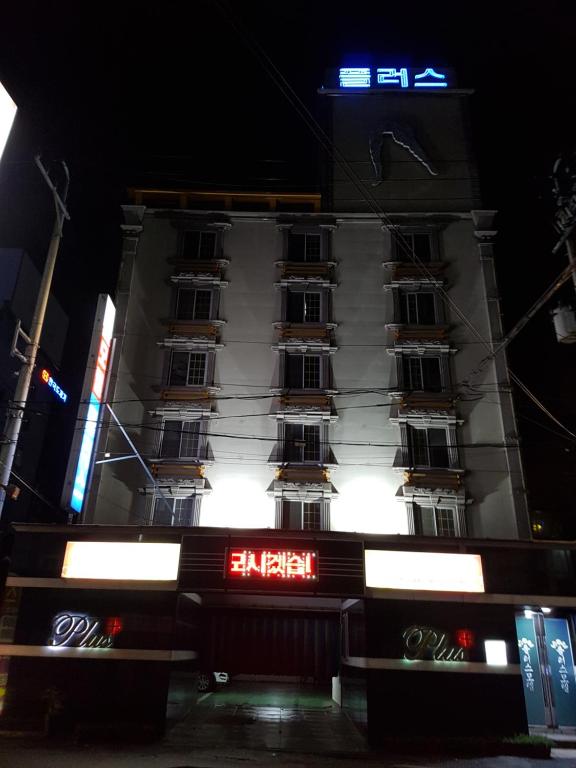 a tall building with neon signs in front of it at Plus Motel in Gwangju