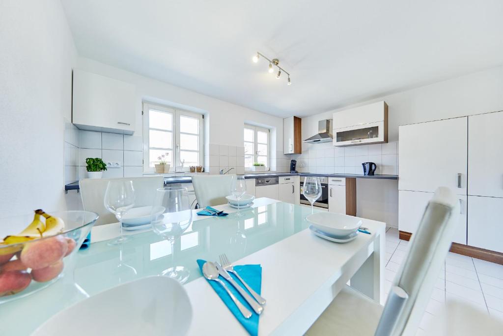 una cocina blanca con una gran mesa de cristal con sillas en Wunderschöne Maisonette-Wohnung für bis zu 10 Personen, en Ettenheim