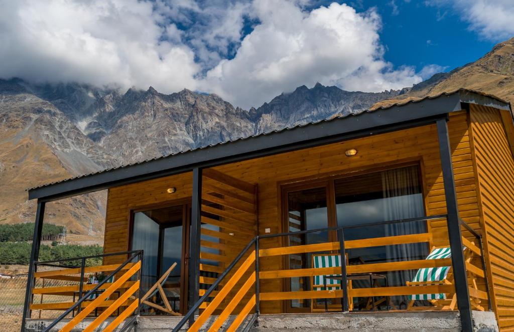 una cabaña de madera con montañas al fondo en Kazbegi 5054 en Kazbegi