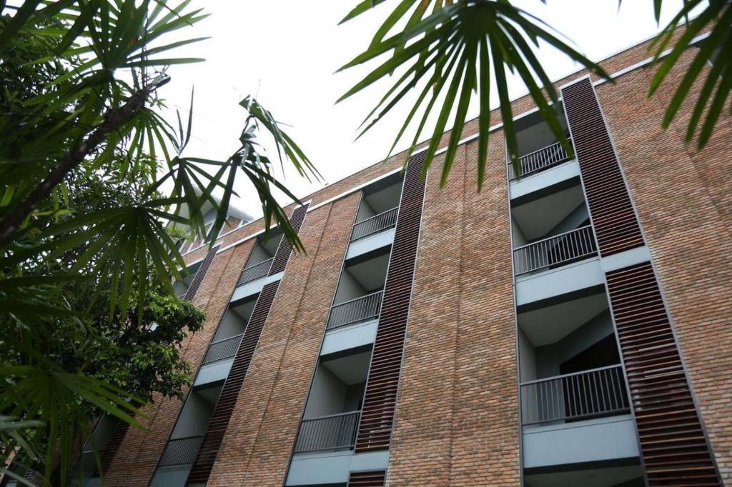 a tall brick building with windows and palm trees at The Coconut Hotel in Lampang