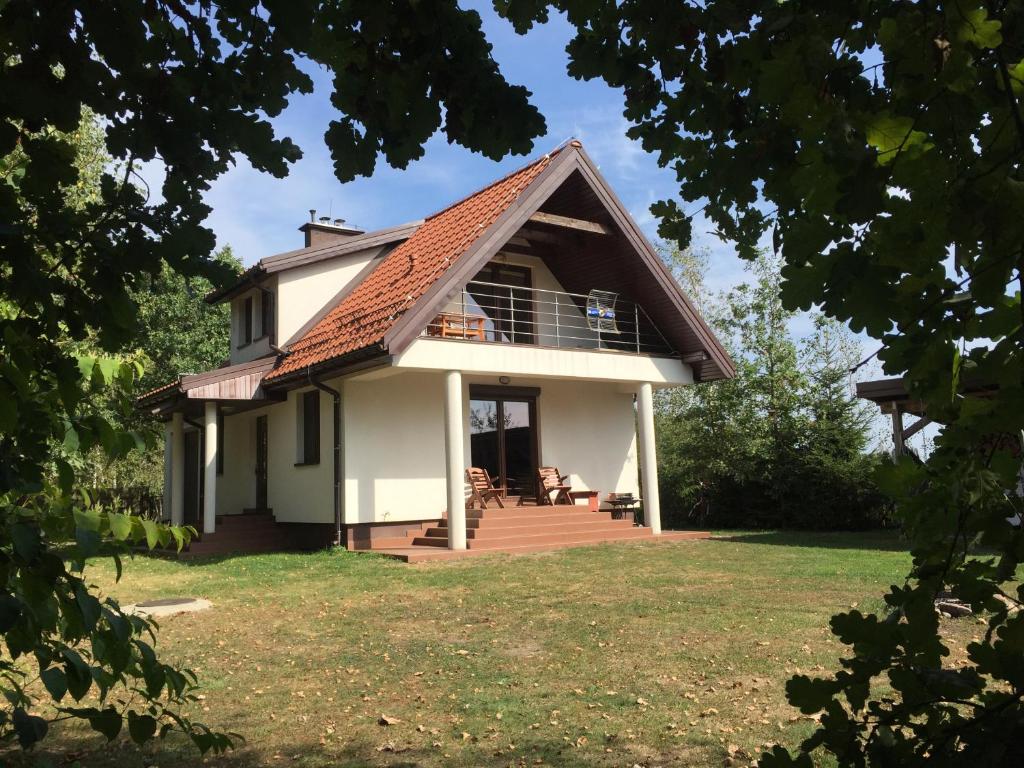 Casa blanca pequeña con porche y balcón en Przystan Kurpiowska en Turośl