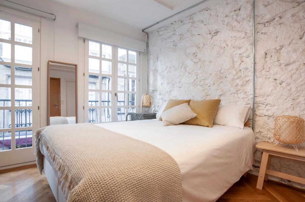 - une chambre avec un grand lit et un mur en pierre dans l'établissement Oktheway Coruña Historic Center, à La Corogne