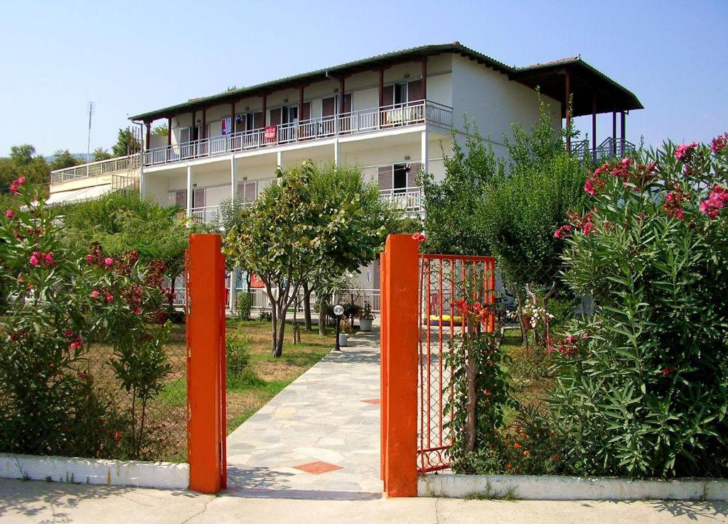 una puerta naranja frente a un edificio con flores en Apartments Ziogas, en Paralía Skotínis
