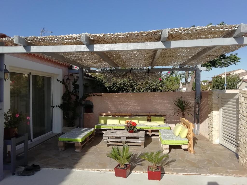 un patio con pergolato, tavolo e panche di la maison du saunier a Salin-de-Giraud