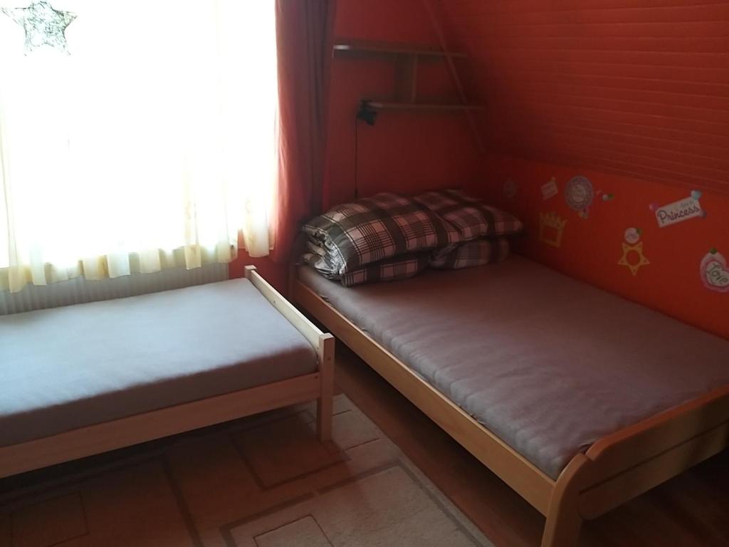 two beds in a small room with a window at Franz Berg Apartman in Tököl