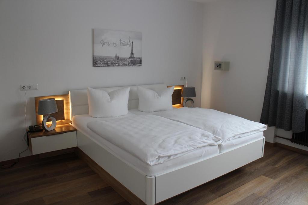 a bedroom with a white bed with two lamps on it at Hotel Glas Schwarzwald in Fluorn