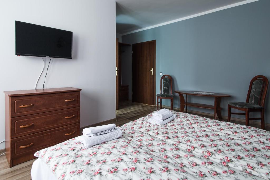 Noclegi Na Granicy في Chyżne: غرفة نوم مع سرير وخزانة وتلفزيون