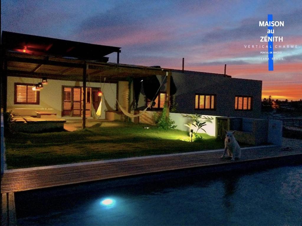 a house with a dog sitting next to a swimming pool at maison au zenit in Maceio