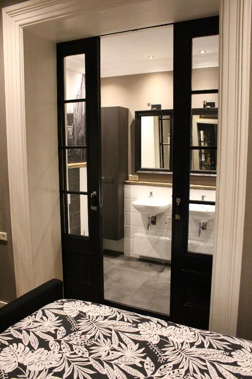 a bedroom with a bed and a sink and a mirror at Logement De drie stokvisschen in Middelburg