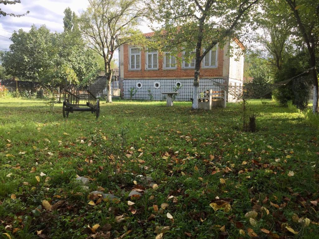 a park with a bench in front of a house at Lazuri Keria Family Guesthouse in Khoni