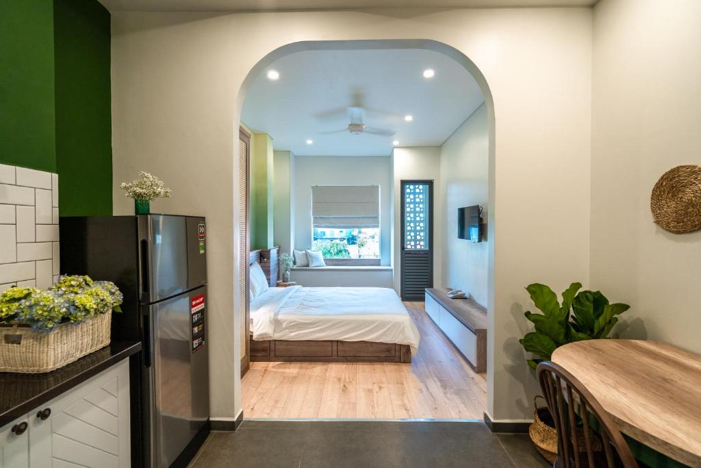 a room with a bed and a kitchen with a refrigerator at Mecozy Apartel in Ho Chi Minh City
