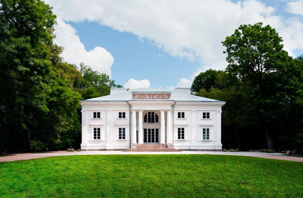una casa blanca con césped delante en Pałac Cieleśnica, en Cieleśnica