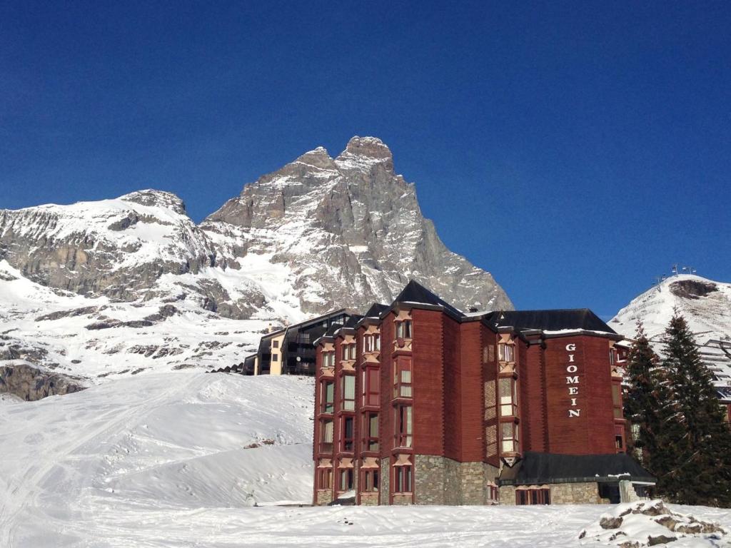 ein Gebäude im Schnee vor einem Berg in der Unterkunft Aura Apartment - Ski In & Ski Out - Cerviniaholidays-com in Breuil-Cervinia