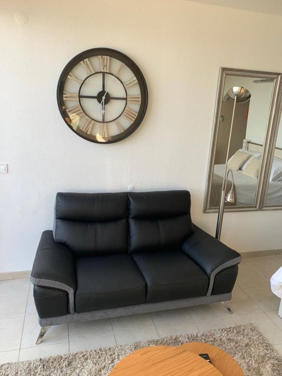 a black couch in a room with a clock on the wall at SOLARIS PANORAMIC studio vue mer in Portimão