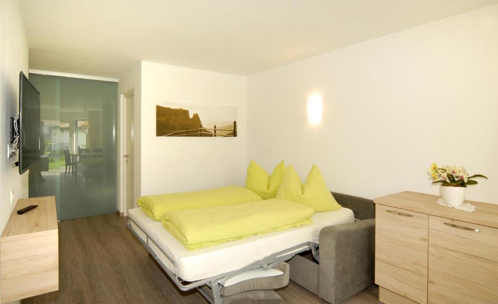 um quarto com uma cama com lençóis amarelos e um sofá em Appartment Charly em Siusi