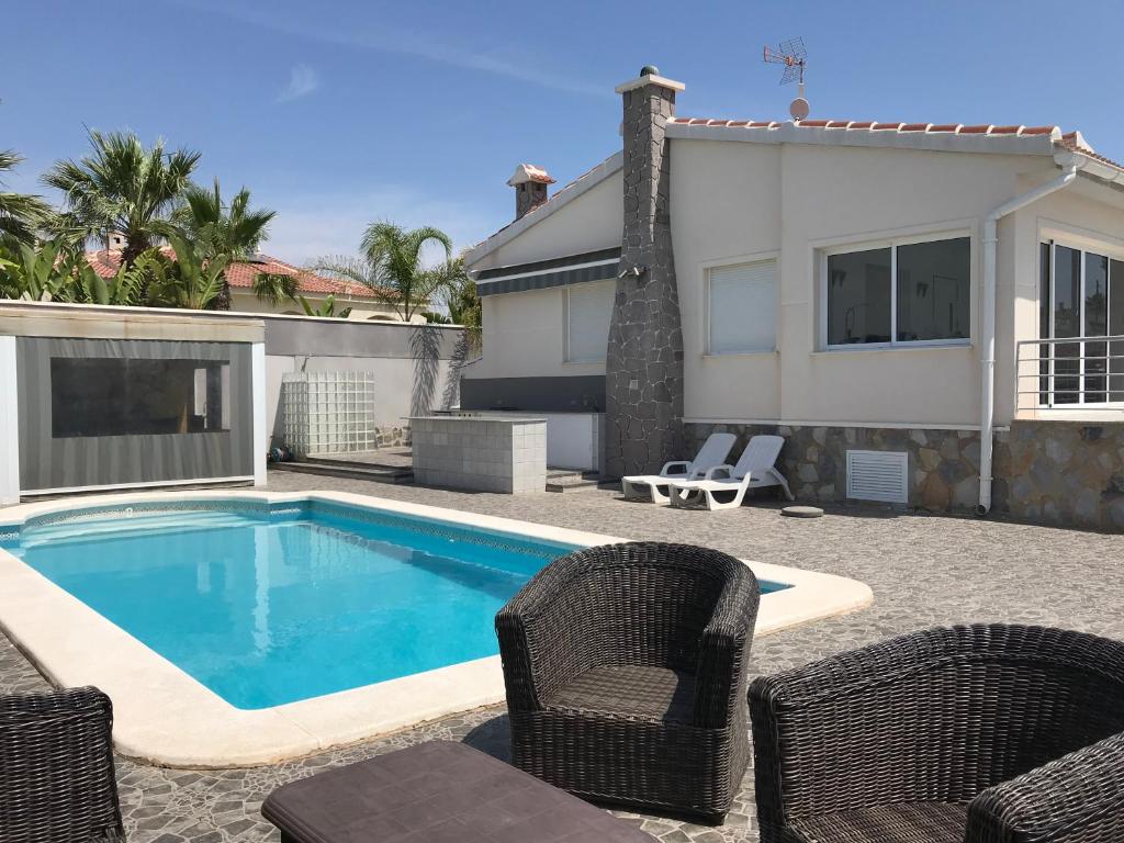 a swimming pool with chairs and a house at Casa Alta - villa med privat svømmebasseng in Ciudad Quesada