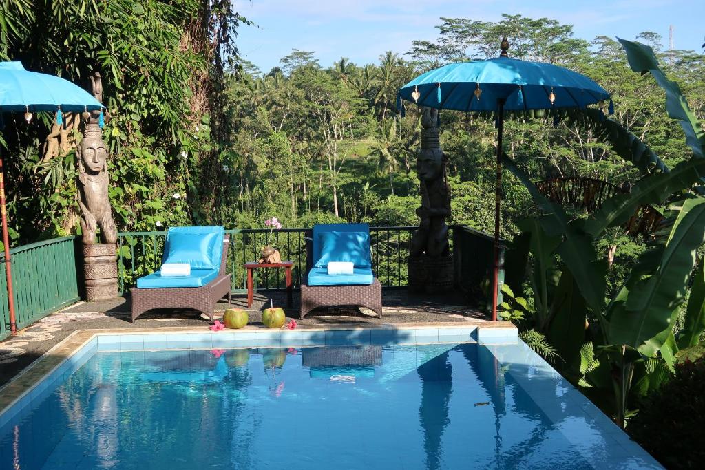 deux chaises et un parasol à côté d'une piscine dans l'établissement Chalet Rabina, à Ubud