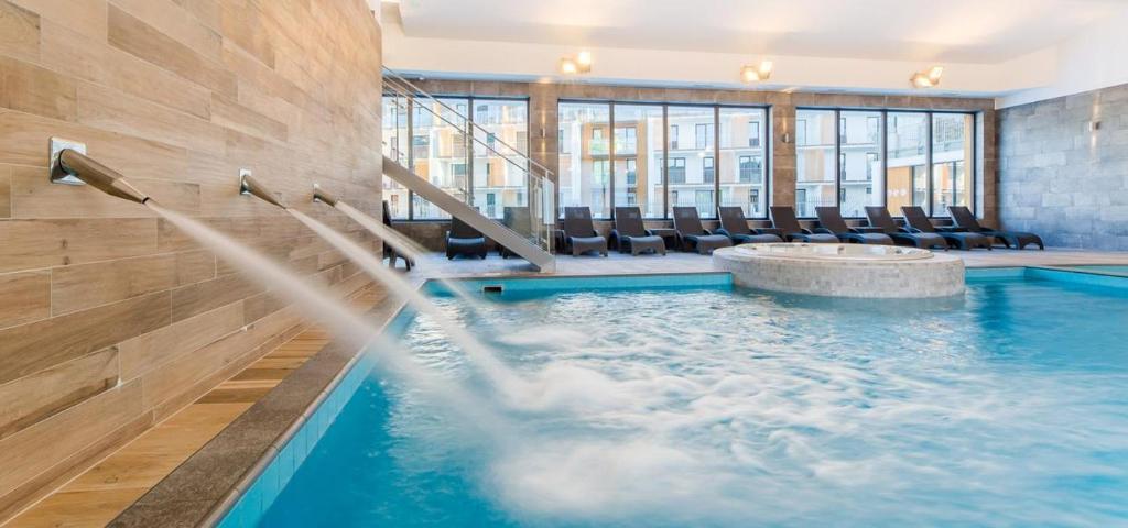 - une piscine avec des chaises dans un bâtiment dans l'établissement Apartament Happy Time SPA - Kołobrzeg, à Kołobrzeg