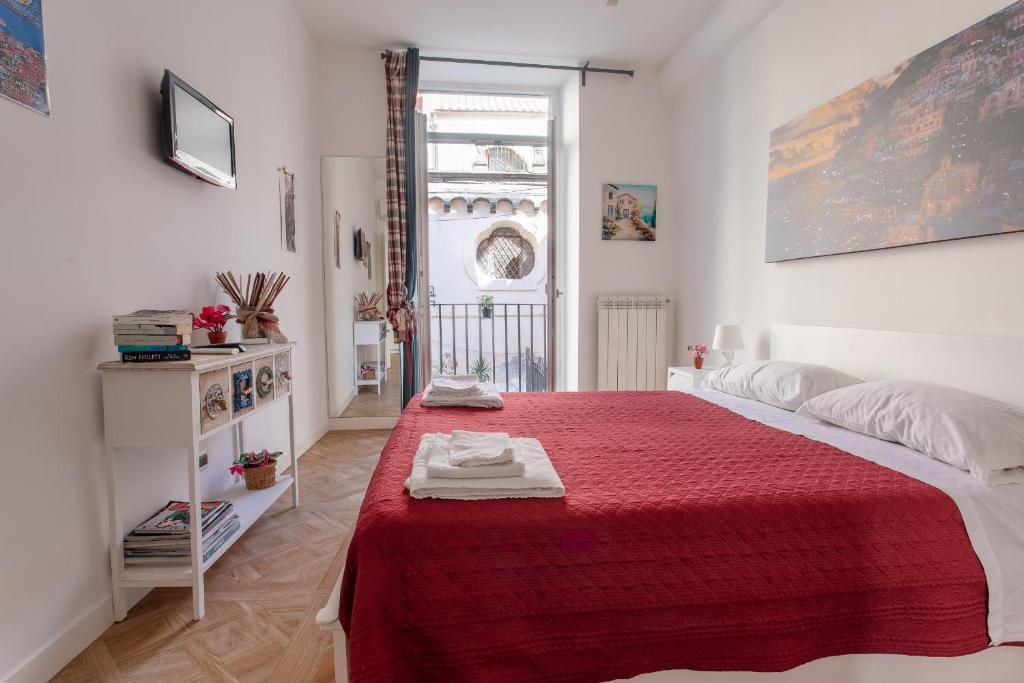 um quarto com uma cama com um cobertor vermelho em Il Balcone Sui Presepi Apartment em Nápoles