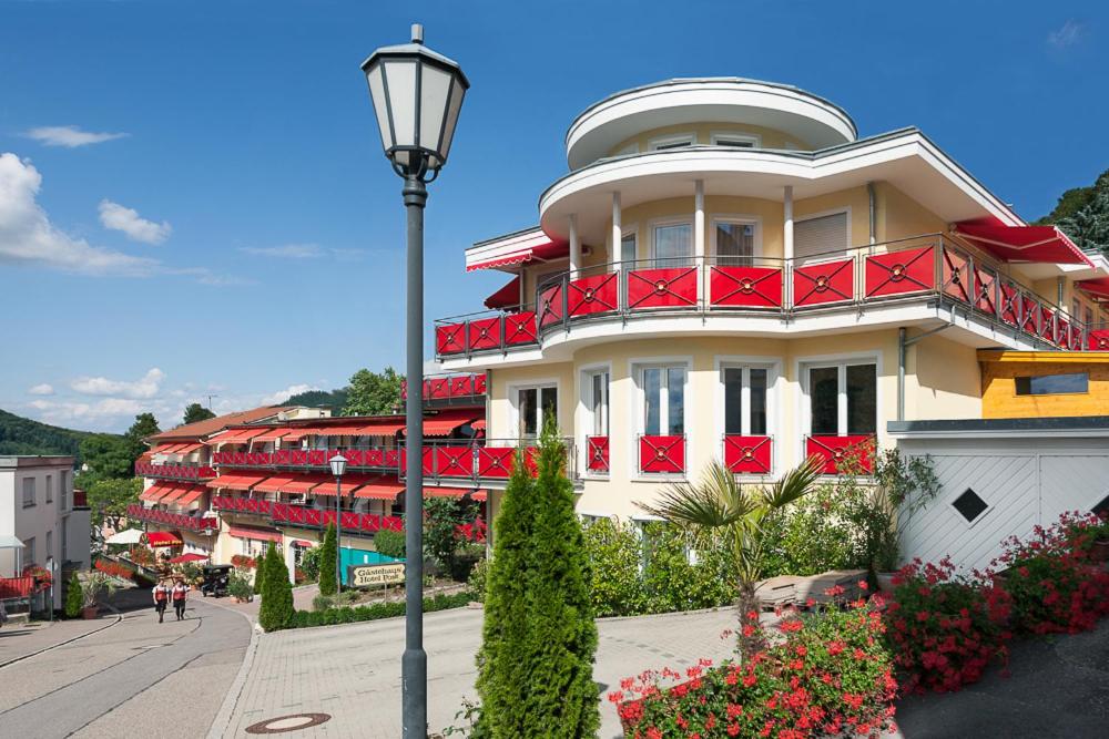 a white building with red balconies and a street light at Wellness Privathotel Post an der Therme in Badenweiler