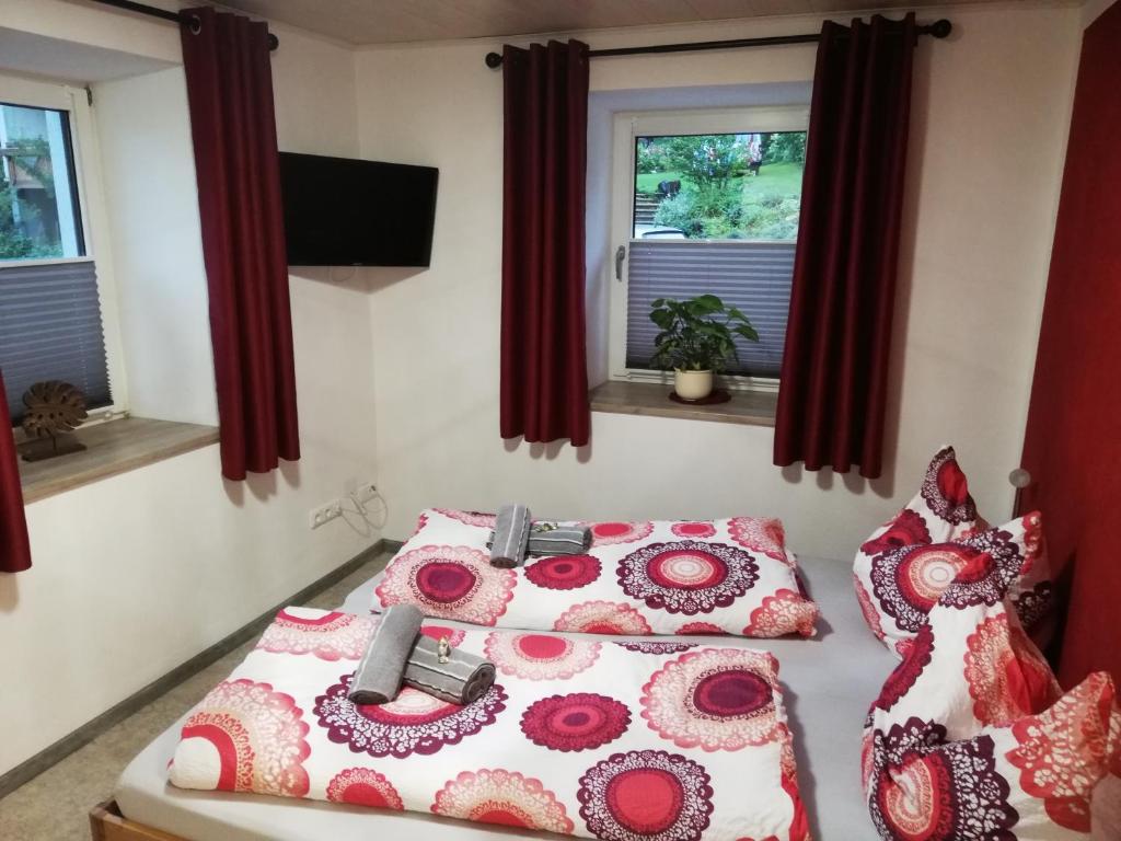 a bedroom with two beds with red curtains and windows at Berg & See Appartements in Hermagor