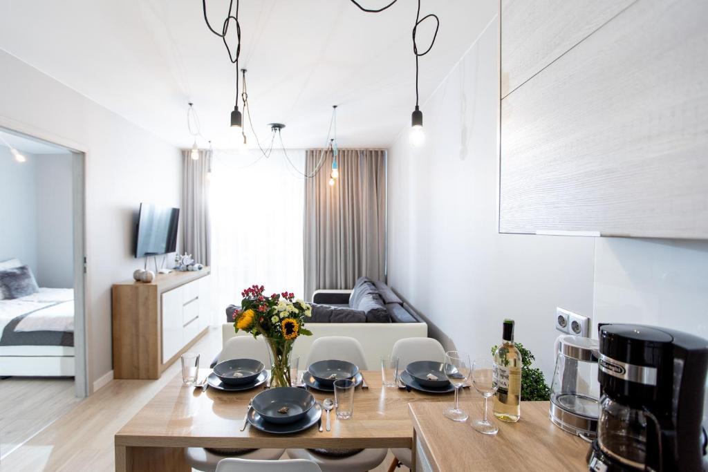 a kitchen and living room with a table and chairs at Apartament Silver Leśne Tarasy in Dziwnówek