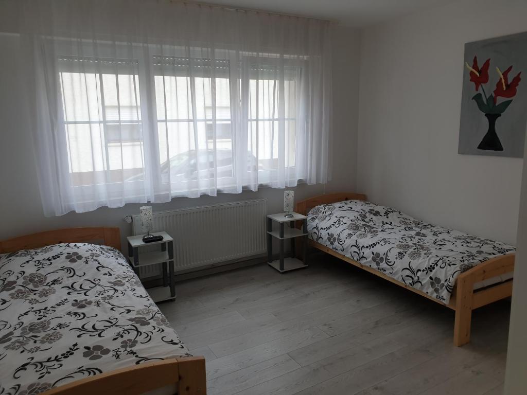 a bedroom with two beds and two windows at Wohnung, Zimmer in Frankfurt Flughafen zu vermieten in Mörfelden-Walldorf
