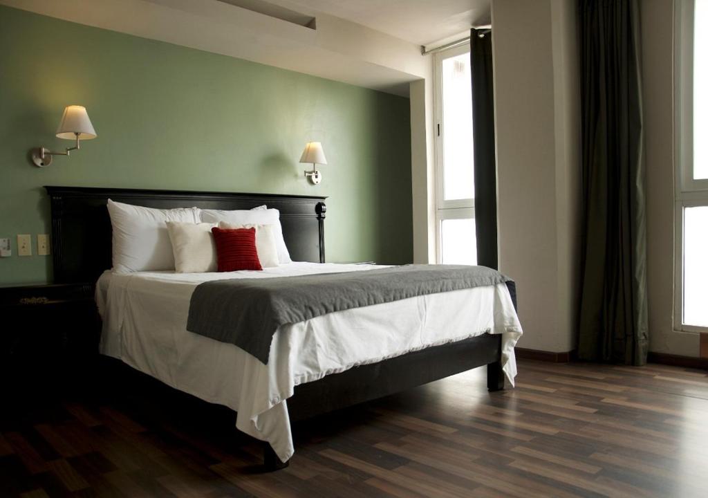 ein Schlafzimmer mit einem großen Bett mit zwei roten Kissen in der Unterkunft Lusitania Suites in Orizaba