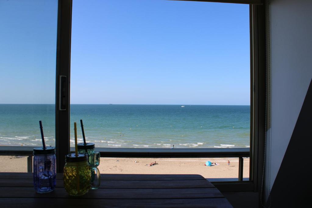 a table with a view of the beach from a window at Le petit coin de Paradis in Varaville