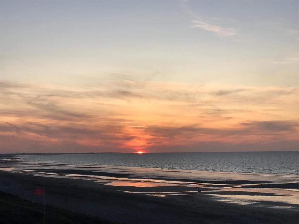 a sunset on the beach with the sun in the distance at Le petit coin de Paradis in Varaville