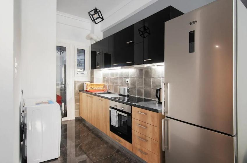 a kitchen with a stainless steel refrigerator and wooden cabinets at Tiny Studio Suite in Athens
