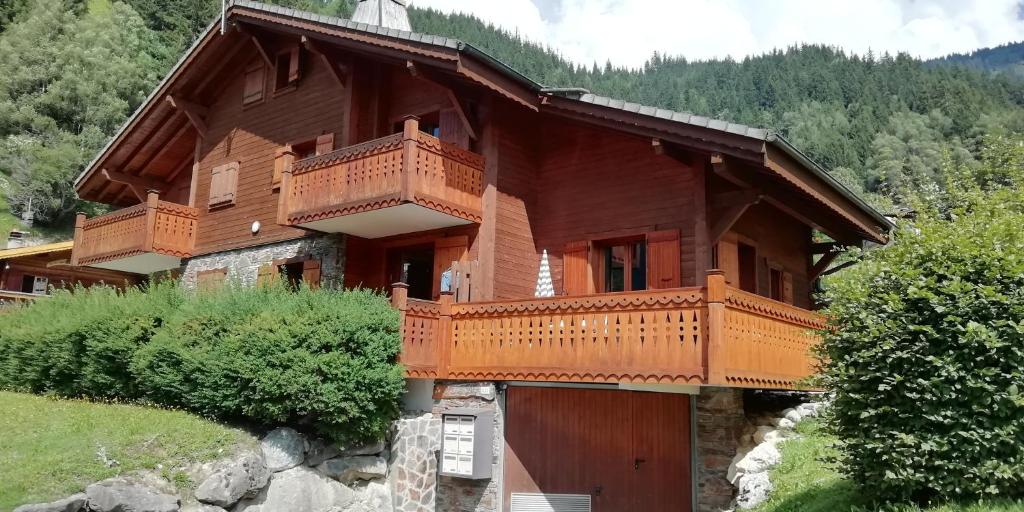 a large wooden house with a balcony on a hill at Le Lièvre Blanc, appartement N°2 in Les Contamines-Montjoie