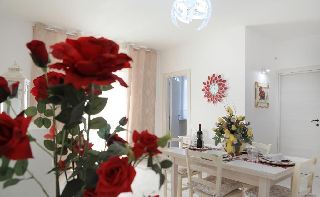 ein Esszimmer mit einem Tisch und roten Rosen in der Unterkunft De Mola Holiday House in Pezze di Greco