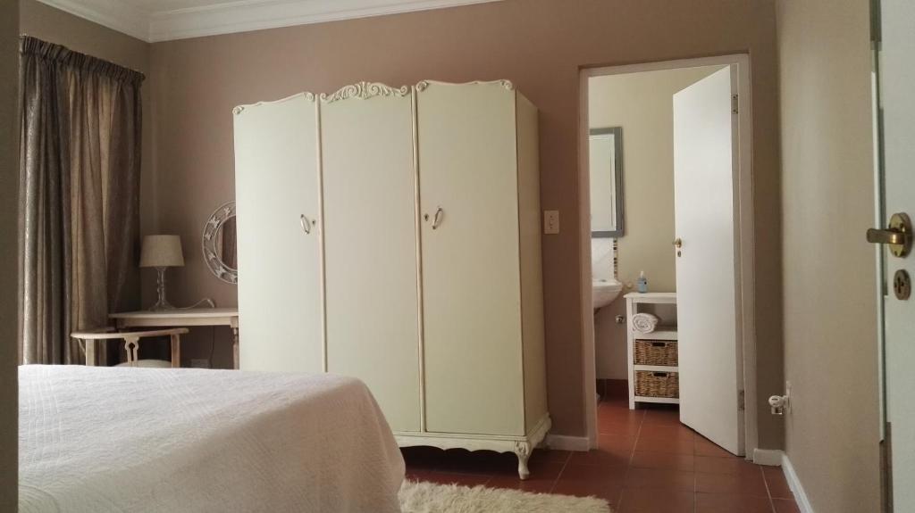 a bedroom with a bed and a white cabinet at Lucias Cottage in Cape Town