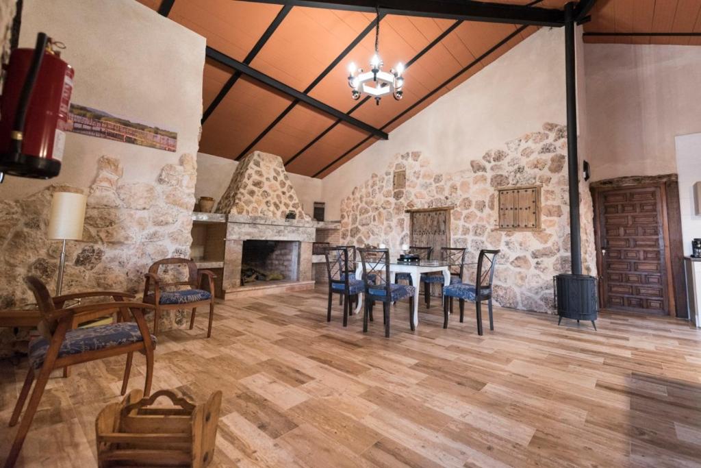 a dining room with a table and chairs and a stone wall at Casa Rural Las Caleras in Daimiel