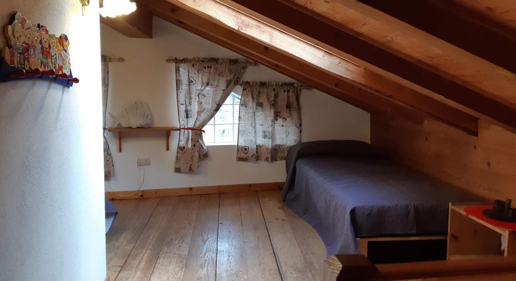 mały pokój z łóżkiem i oknem w obiekcie Casetta con camino w mieście La Magdeleine