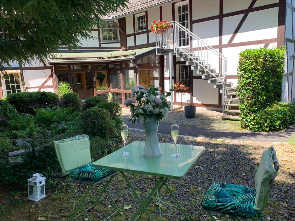 a table with a vase of flowers and two chairs at Waldstudio Comfort in Simmerath