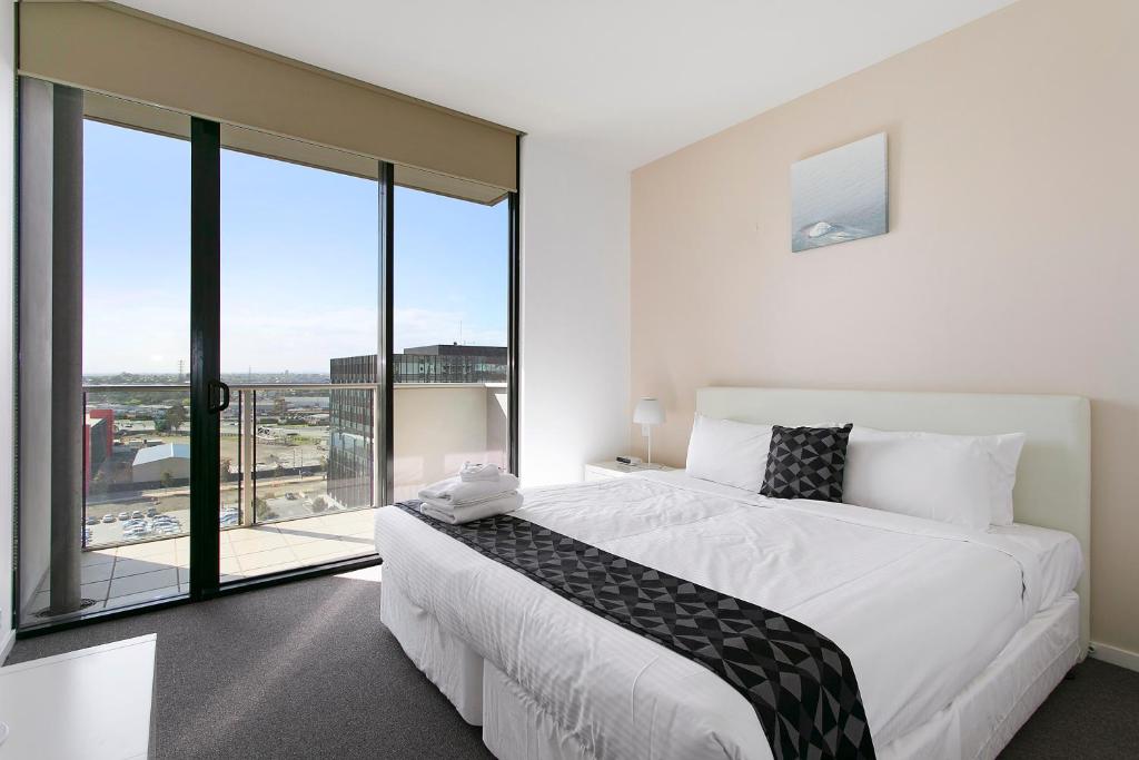 a bedroom with a large bed and a large window at Docklands Private Collection - NEWQUAY in Melbourne
