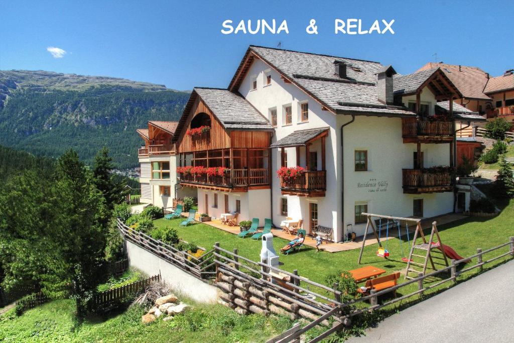 a large house on a hill with a yard at Dolomites Apartments Ciasa Vally in San Cassiano