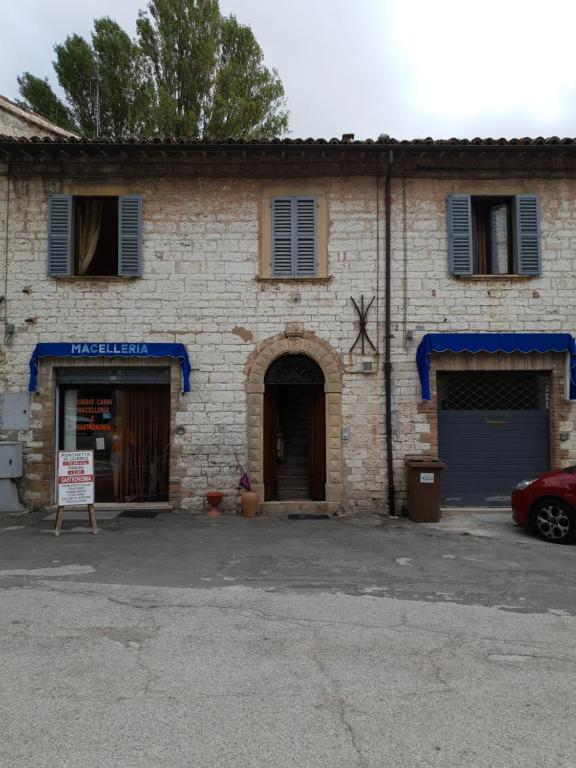 un bâtiment en briques avec deux portes et une voiture garée devant dans l'établissement La Casa in Piazza, à Gubbio