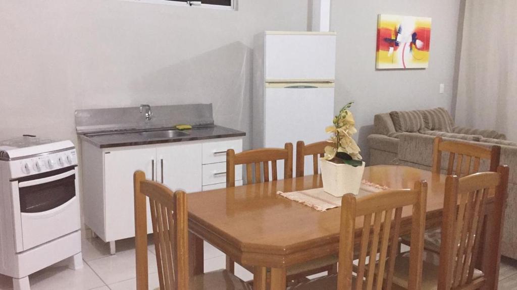 uma cozinha com uma mesa de madeira com cadeiras e uma cozinha com um frigorífico em Loft - Aeroporto em Florianópolis