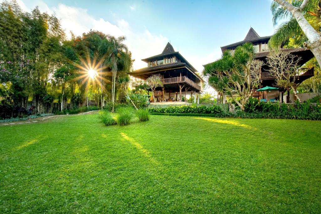 ein grüner Hof mit einem Haus im Hintergrund in der Unterkunft Villa Atas Awan in Payangan