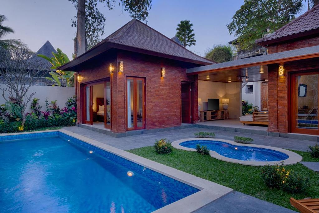 a house with a swimming pool in front of a house at Kutus Kutus Mas Ubud Villa in Ubud