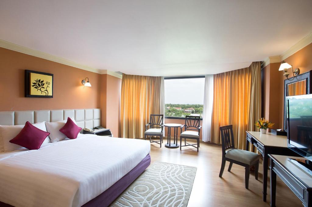 um quarto de hotel com uma cama, uma secretária e uma televisão em The Imperial Hotel & Convention Centre Phitsanulok em Phitsanulok