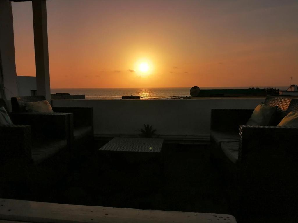 a sunset over the ocean from a balcony with couches at Apartamentos Flor del Cotillo in El Cotillo