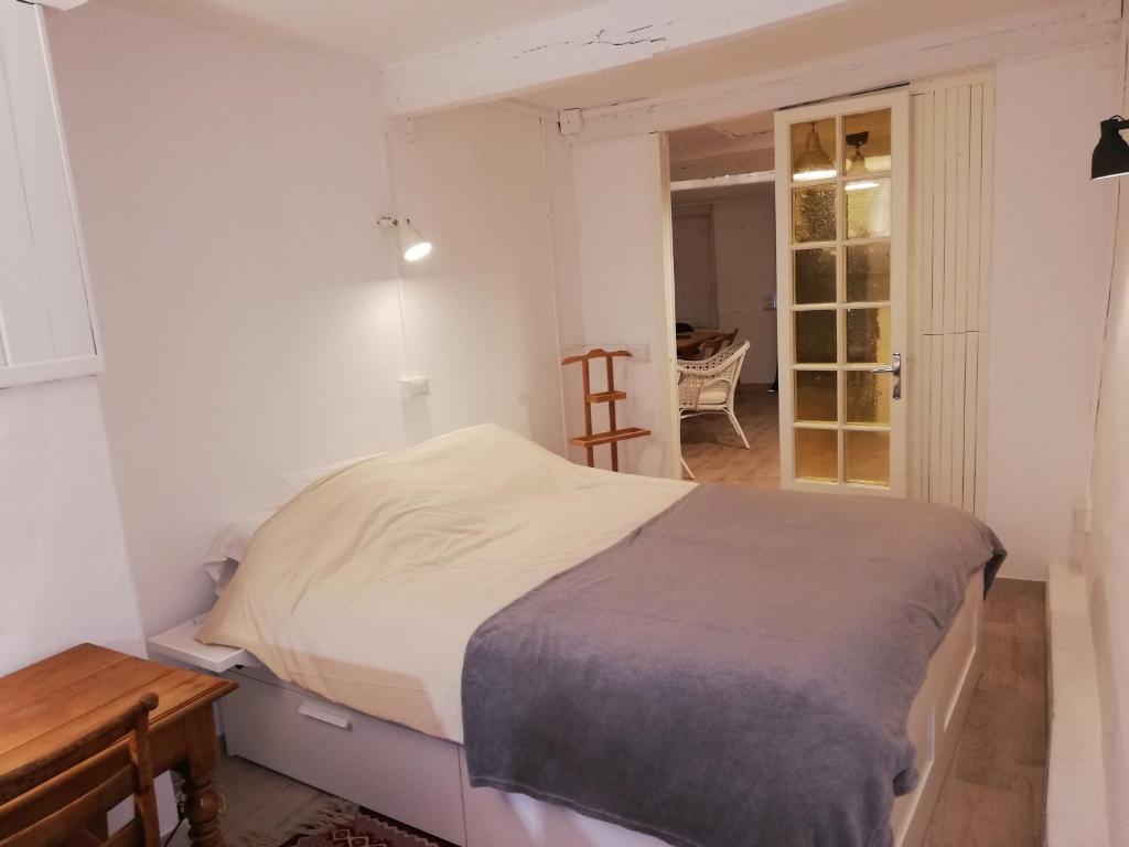 a white bedroom with a bed and a table at Au coeur de Tende in Tende