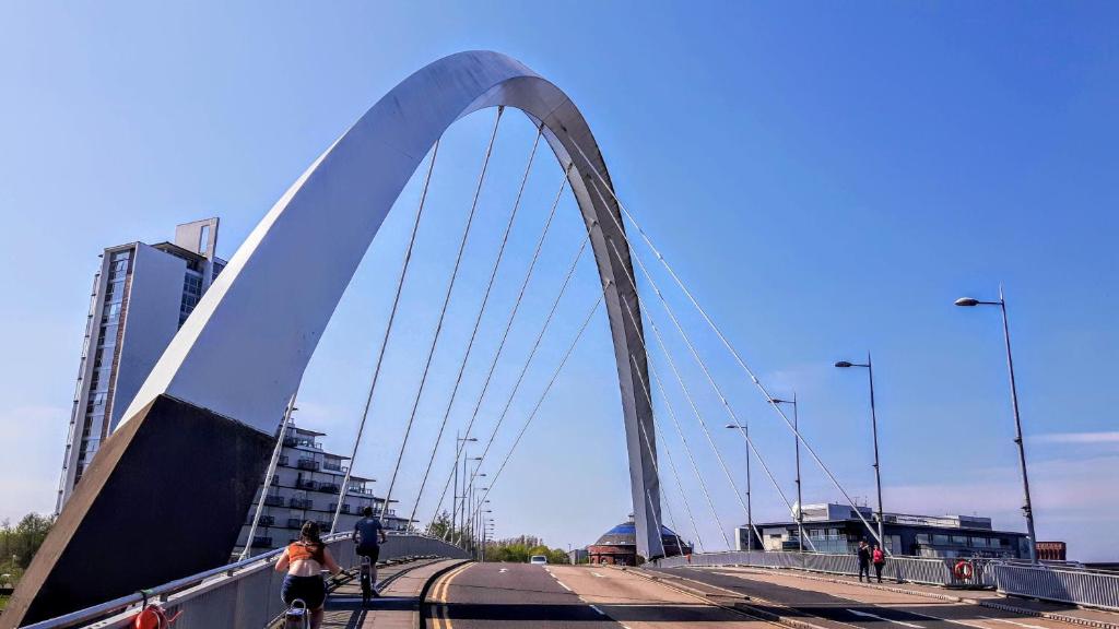 a bridge over a river with people riding bikes on it at Elegant Apartment Near SECC/HYDRO in Finnieston, Glasgow in Glasgow